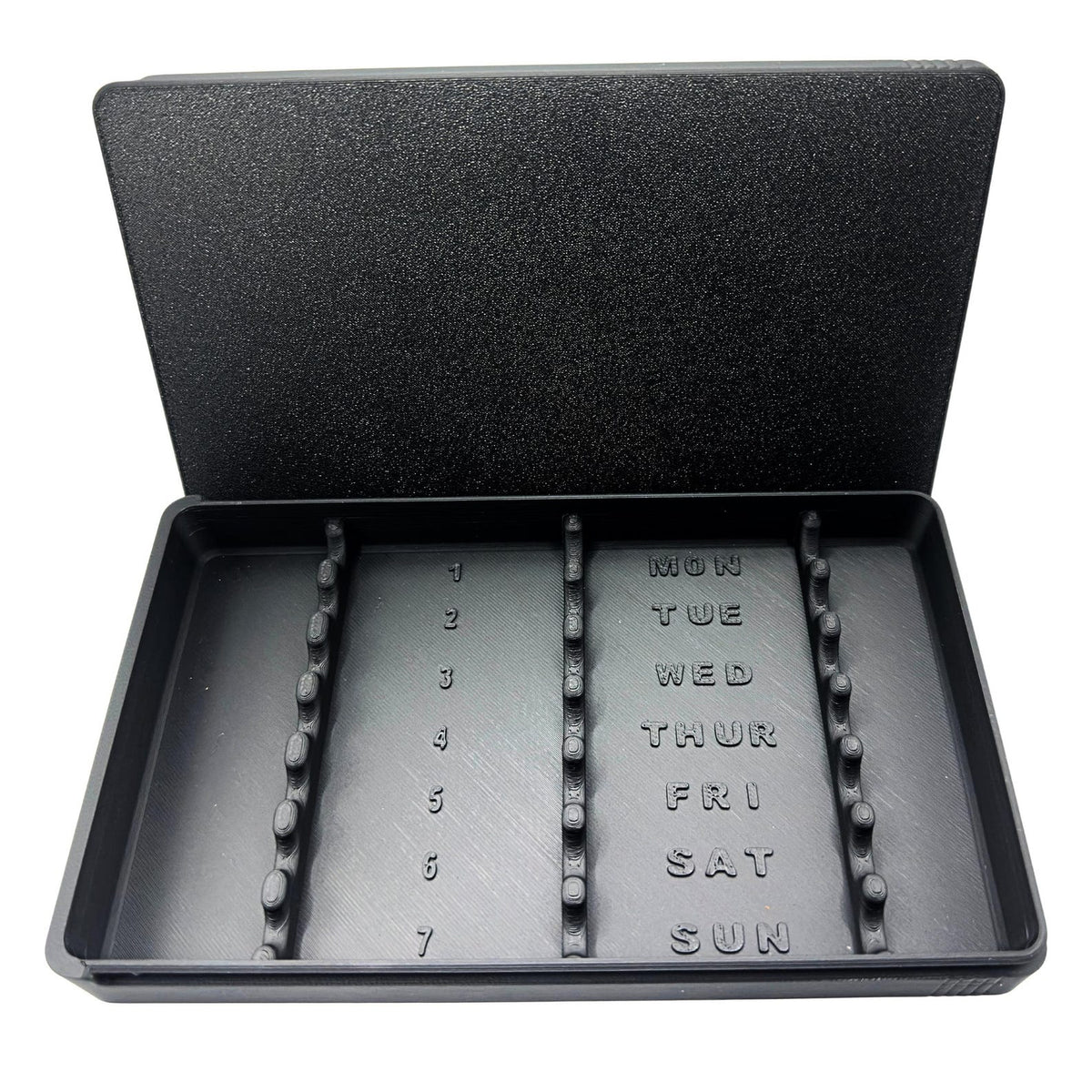 7-slot weekly syringe organizer case shown empty to display interior layout. Numbered slots 1 through 7 with day-of-week labels Monday through Sunday and raised dividers for syringe separation. Black prefilled syringe storage case with sliding lid, designed for 1ml insulin syringes up to 180mm long.